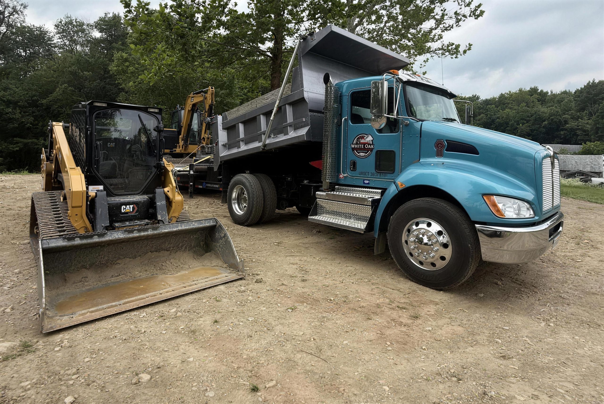 White Oak dump truck, CAT skid steer, and mini excavator lined up in LaGrangeville, NY